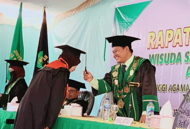 
Foto: Ketua STAI Babussalam Sula, Maluku Utara, Dr. Sahrul Takim, saat memindahkan tali toga kepada salah satu wisudawati. (Dok: bacaritamalut.com)